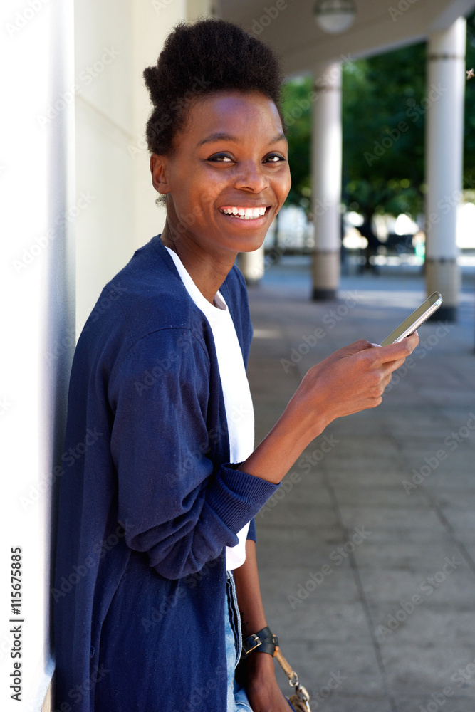 Happy young woman standing outdoors with a mobile phone Happy young woman standing outdoors with a mobile phone
