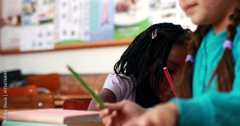 Little girl colouring in the classroom in elementary school Little girl colouring in the classroom in elementary school