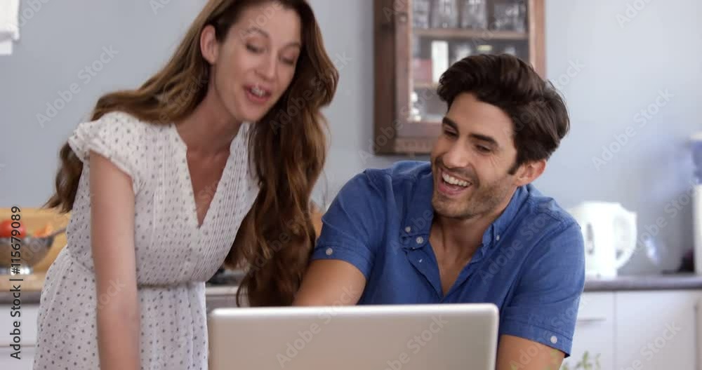 Cute couple looking at laptop and cooking Cute couple looking at laptop and cooking