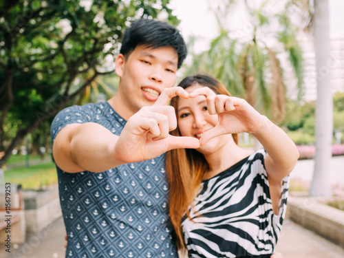 Closeup shot of young loving couple making heart shape with hand
