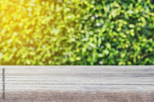 Wooden desk with defocus green bush with bokeh, vintage tone