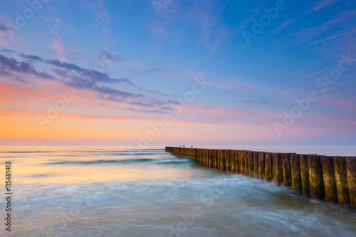 sunset on the beach with a wooden breakwater, long exposure © dziewul