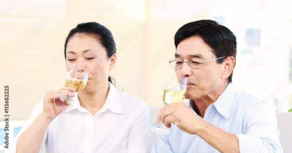 Mature couple tasting champagne on the sofa in the living room Mature couple tasting champagne on the sofa in the living room