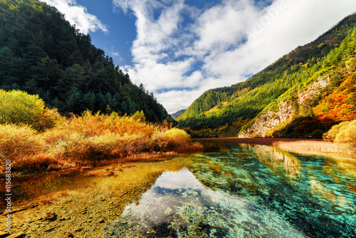 Amazing crystal clear water of river among mountains in autumn