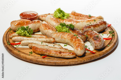 Different kind of grilled sausages on the wooden plate on white background