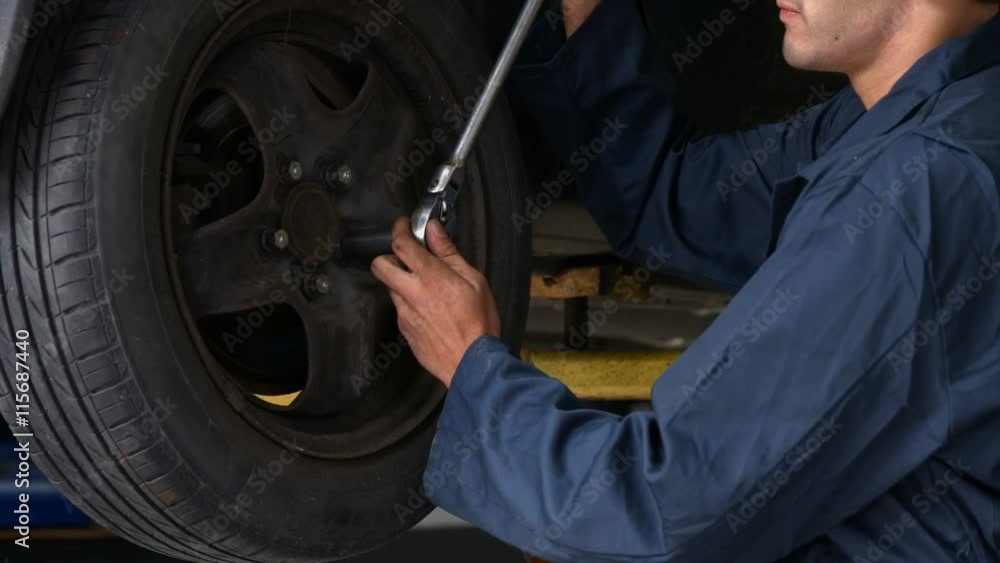 Handsome mechanic repairing a car in the garage Handsome mechanic repairing a car in the garage