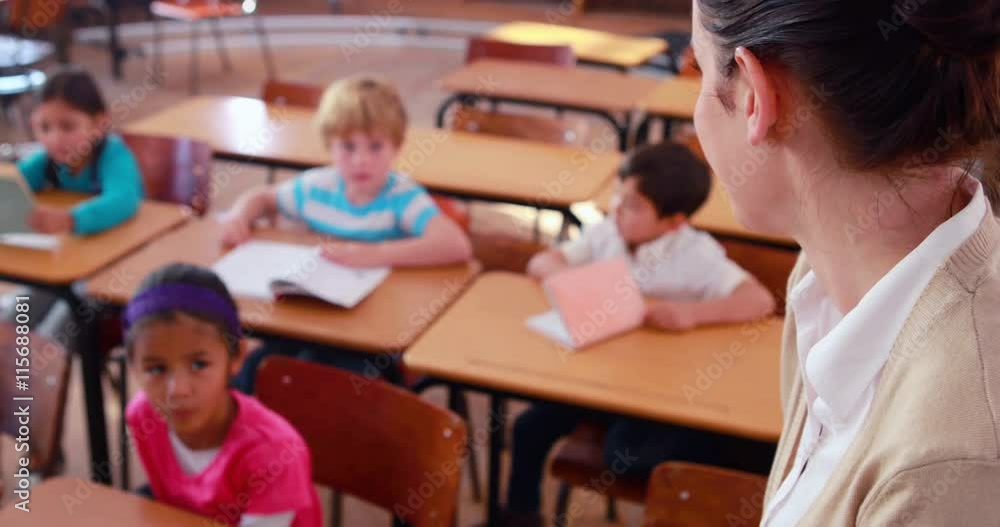 Pretty teacher smiling at camera at top of classroom Pretty teacher smiling at camera at top of classroom
