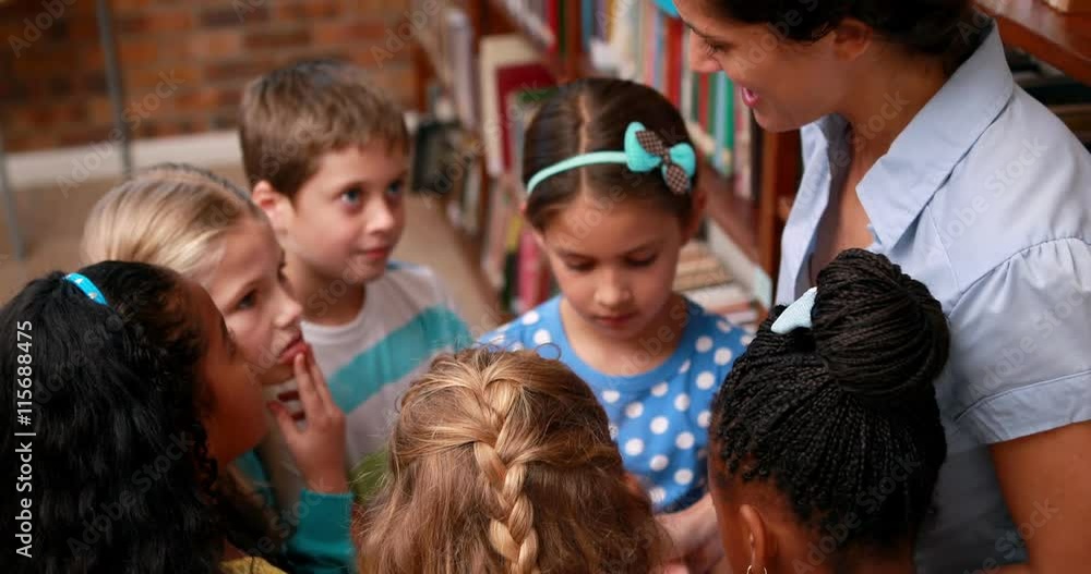 Pupils talking with their teacher in the library in elementary school Pupils talking with their teacher in the library in elementary school