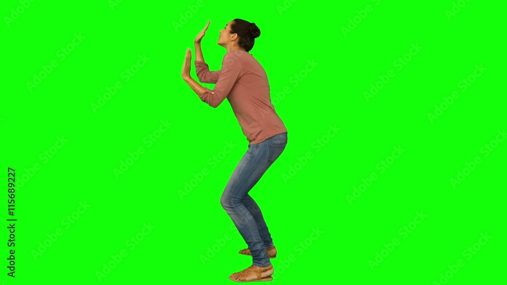 Casual woman crouching with hands up on green screen background Casual woman crouching with hands up on green screen background
