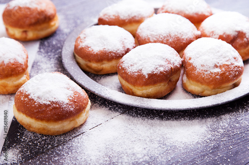 German donuts - berliner with jam and icing sugar in a tray on a dark wooden background. Space for text
