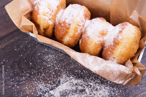 German donuts - delicious berliner with jam and icing sugar in a box on a dark wooden background. Space for text
