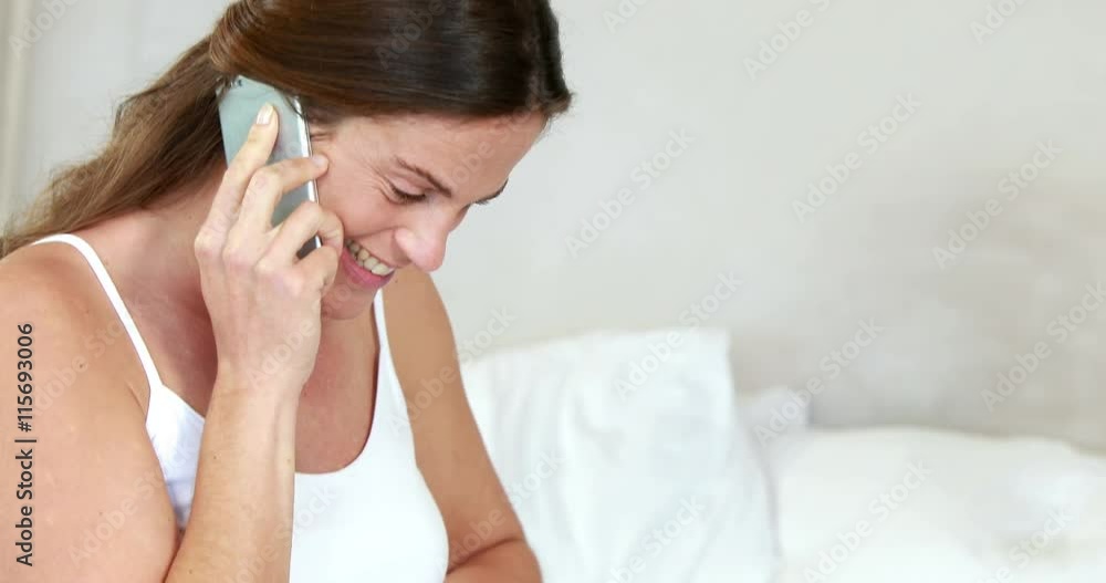 Pregnant woman relaxing on bed talking on phone Pregnant woman relaxing on bed talking on phone