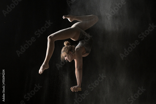 Fototapeta Naklejka Na Ścianę i Meble -  Gymnastic flexible woman handstand on equilibr at sprinkled flour