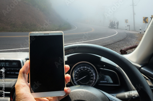 Hand hold smartphone in vehicle on the fog road