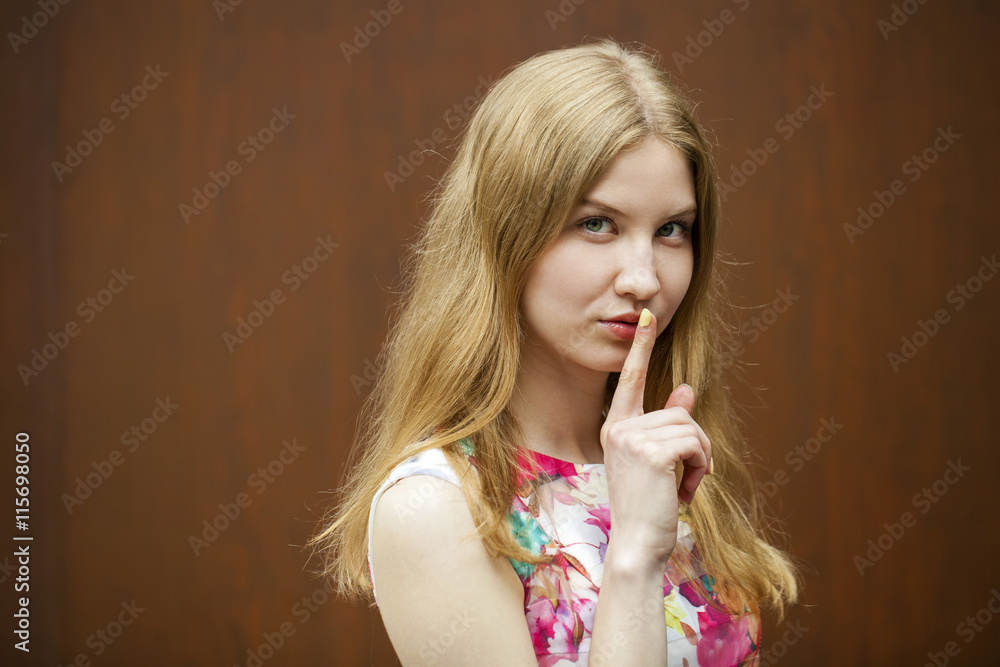 Young beautiful blonde woman has put forefinger to lips as sign Young beautiful blonde woman has put forefinger to lips as sign