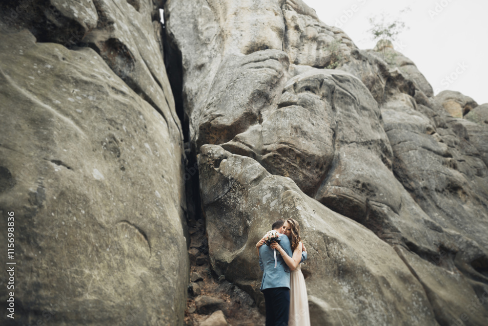 Happy wedding couple kissing and hugging near a high cliff Happy wedding couple kissing and hugging near a high cliff