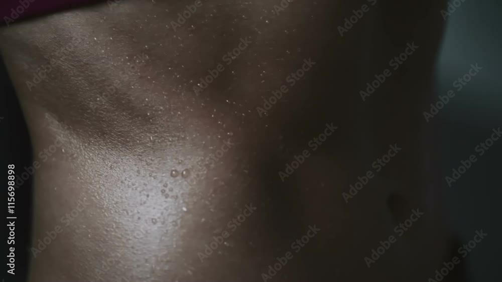 Close up of wet tanned female skin on torso in dark studio Close up of wet tanned female skin on torso in dark studio