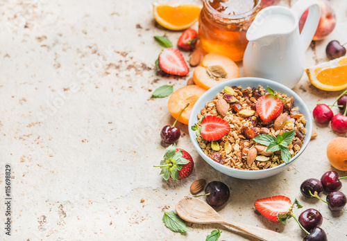 Healthy breakfast ingredients. Bowl of oat granola with milk, fresh fruit, berries and honey