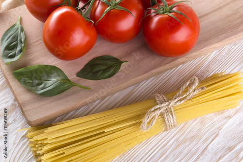 Raw pasta and ingredients with tomatoes, basil.