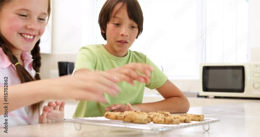Siblings eating hot cookies from the cooling rack Siblings eating hot cookies from the cooling rack
