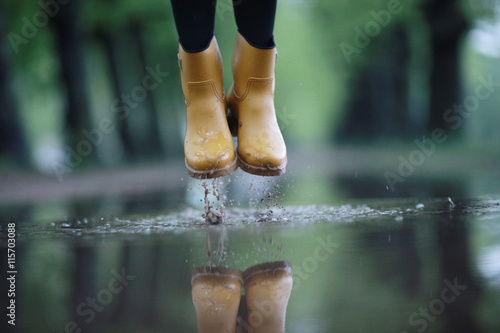 feet in rubber boots rain puddle city photo