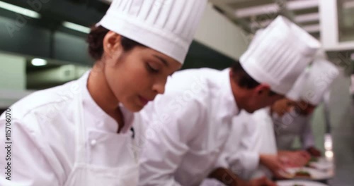 Team of chefs garnishing spaghetti dishes with basil leaf