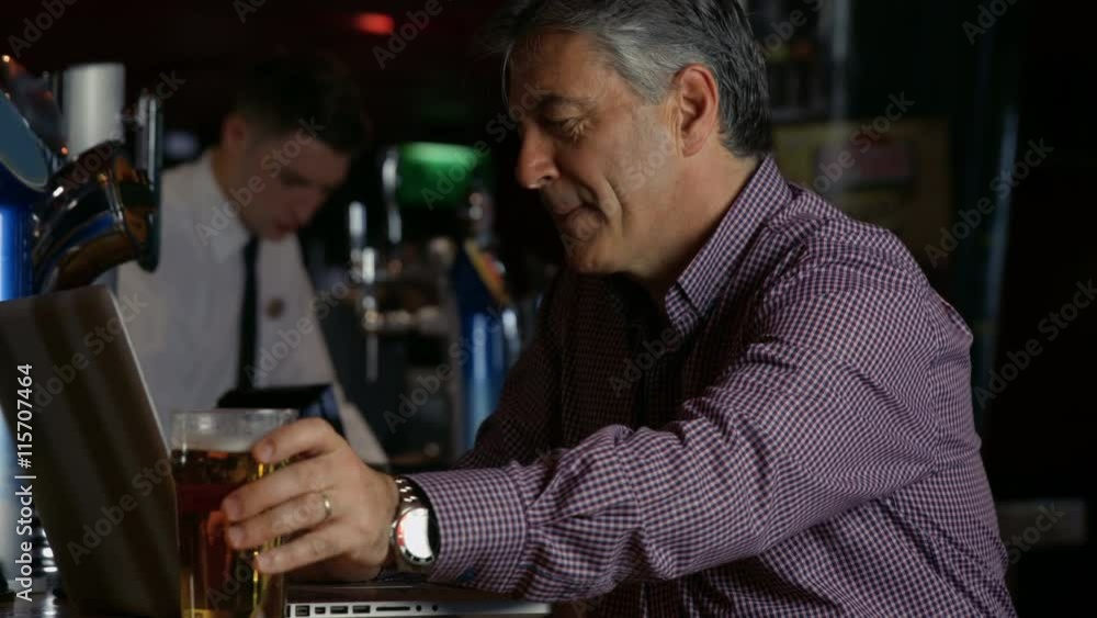 Man having a pint at the bar using laptop in high quality 4k format Man having a pint at the bar using laptop in high quality 4k format