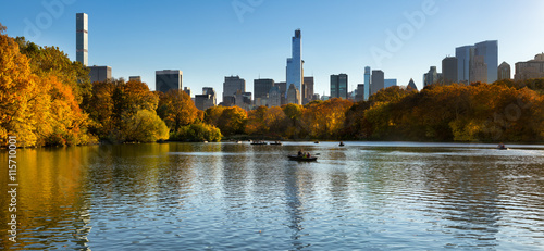 Fall in Central Park at The Lake with Midtown Manhattan skyscrapers. Panoramic afternoon cityscape view with colorful fall foliage. Manhattan  New York City