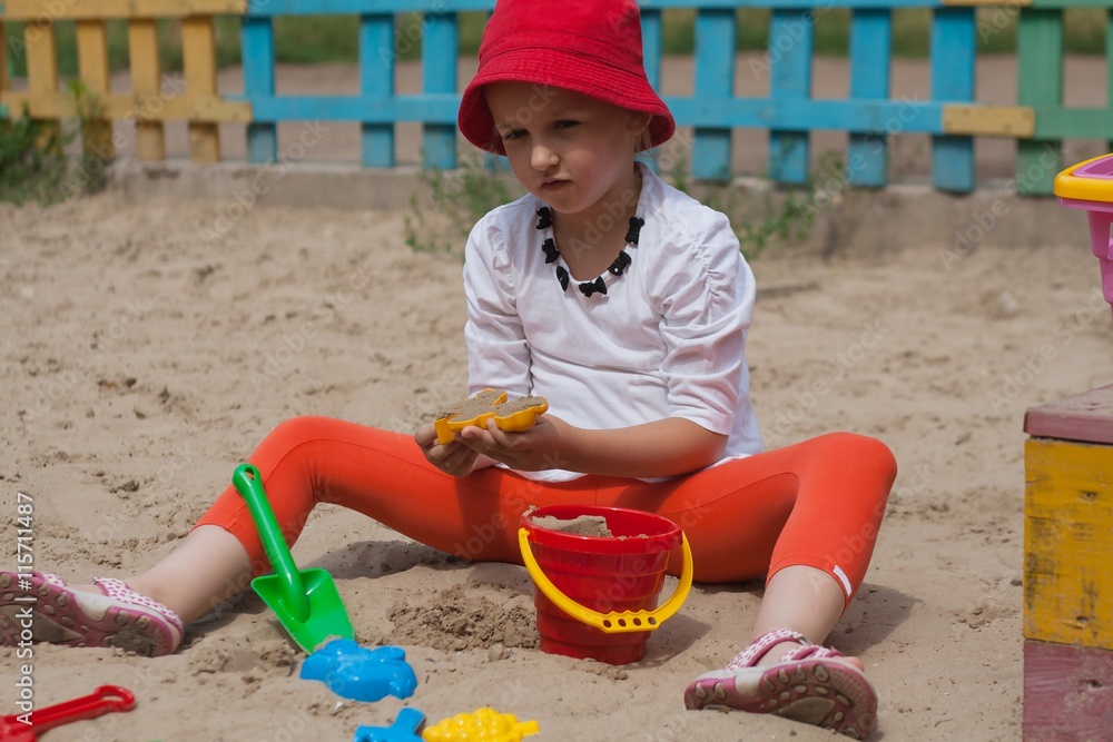 The child plays in a sandbox. Children's playground. Game with sand in a sandbox. To mold from sand. The child plays in a sandbox. Children's playground. Game with sand in a sandbox. To mold from sand.