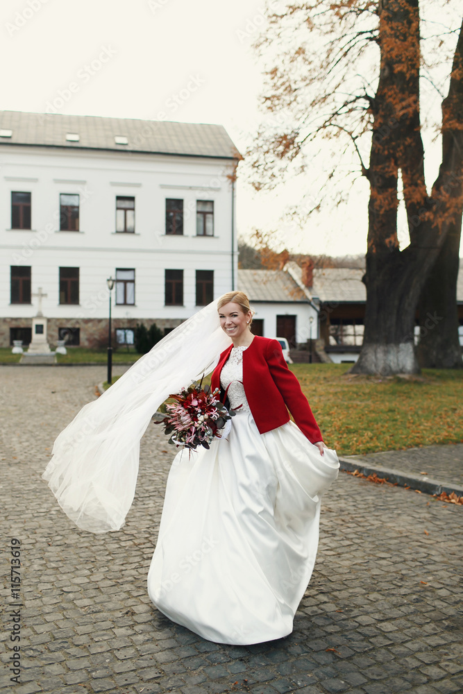 Bride plays with a dress standing in the autumn park