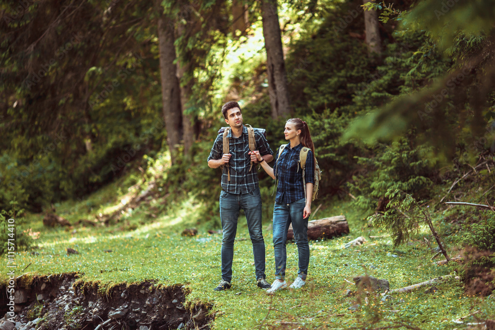 A couple hikers Hiking with backpacks walk along a beautiful mountain area. The concept of active rest A couple hikers Hiking with backpacks walk along a beautiful mountain area. The concept of active rest