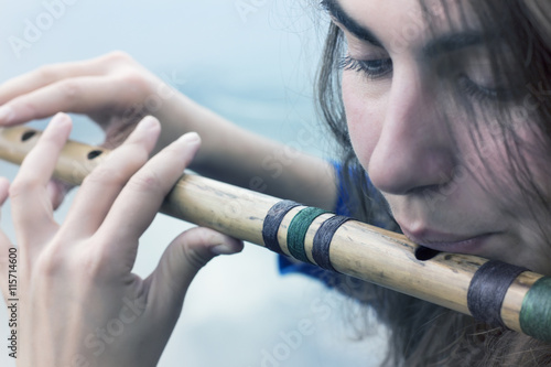 Musician playing a wooden flute on the banks of the river photo