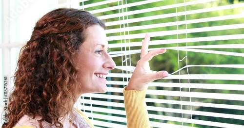 Woman peering through roller blind photo