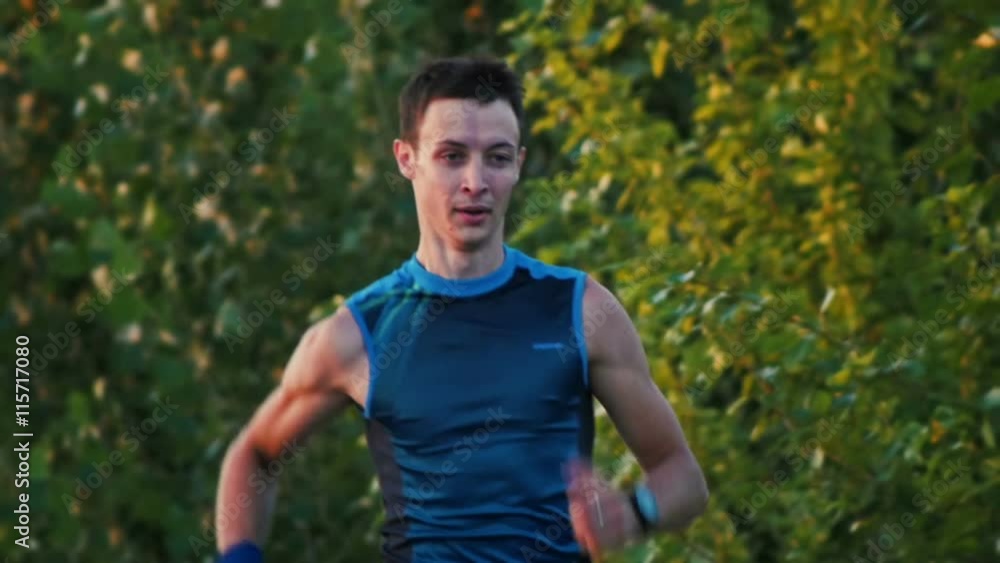 Portrait of a runner man running in park at dusk, slow-motion Portrait of a runner man running in park at dusk, slow-motion