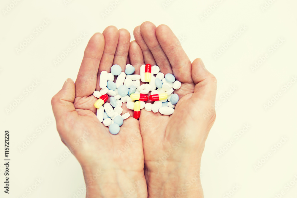 close up of senior woman hands with pills