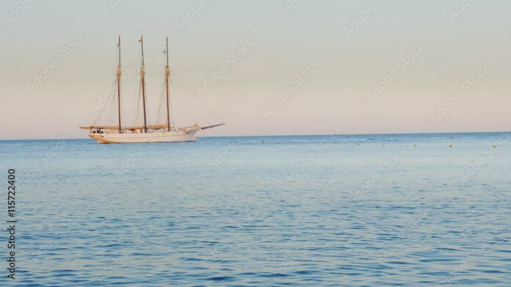A ship with three masts with deflated sails. Drift in the sea at sunset A ship with three masts with deflated sails. Drift in the sea at sunset