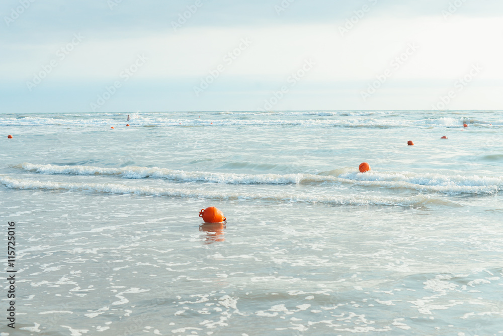 Vacation view background: calm shiny sea in the morning with red buoys, concept of freedom and tranquility
