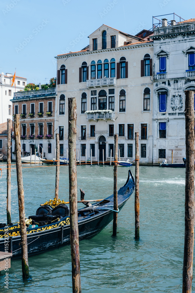 Travel photo: view on Grand Canal, gondola berthed between piles and ancient historical houses in Venice, Italy, popular touristic place