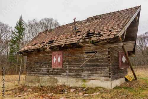 Old rural abandoned wooden collapsing house agains cloudy sky in autumn season