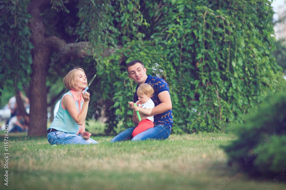 Happy family of three lying in the grass . Warm effect added. Happy family of three lying in the grass . Warm effect added.