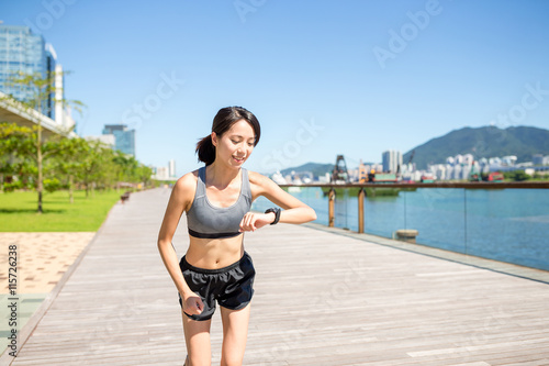 Woman running in a city and checking on smart watch © leungchopan