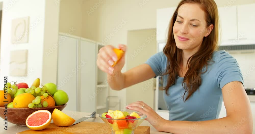 Pretty woman preparing a fruit salad smiling at camera Pretty woman preparing a fruit salad smiling at camera