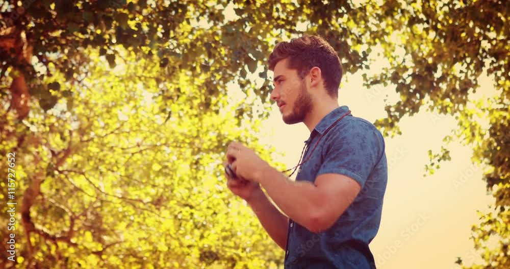 Handsome man using retro photo camera in the park Handsome man using retro photo camera in the park