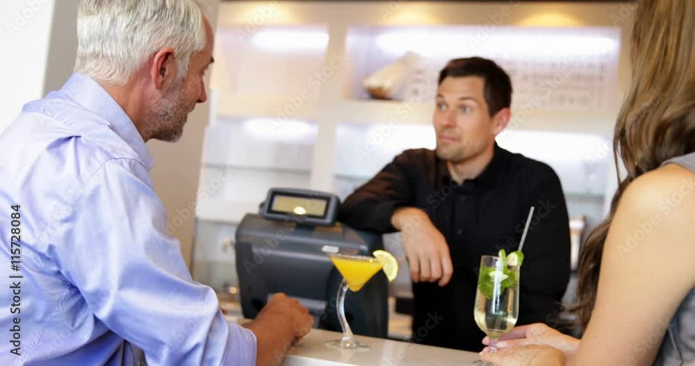 Bartender serving cocktails and chatting to customers Bartender serving cocktails and chatting to customers