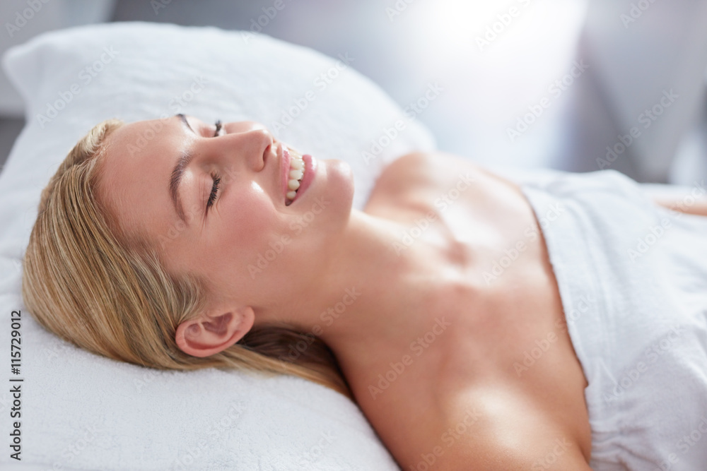 Smiling woman in a day spa relaxing on massage table Smiling woman in a day spa relaxing on massage table