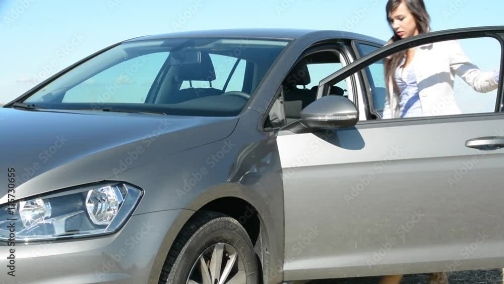 young attractive woman gets in the car in the countryside - holds steering wheel young attractive woman gets in the car in the countryside - holds steering wheel