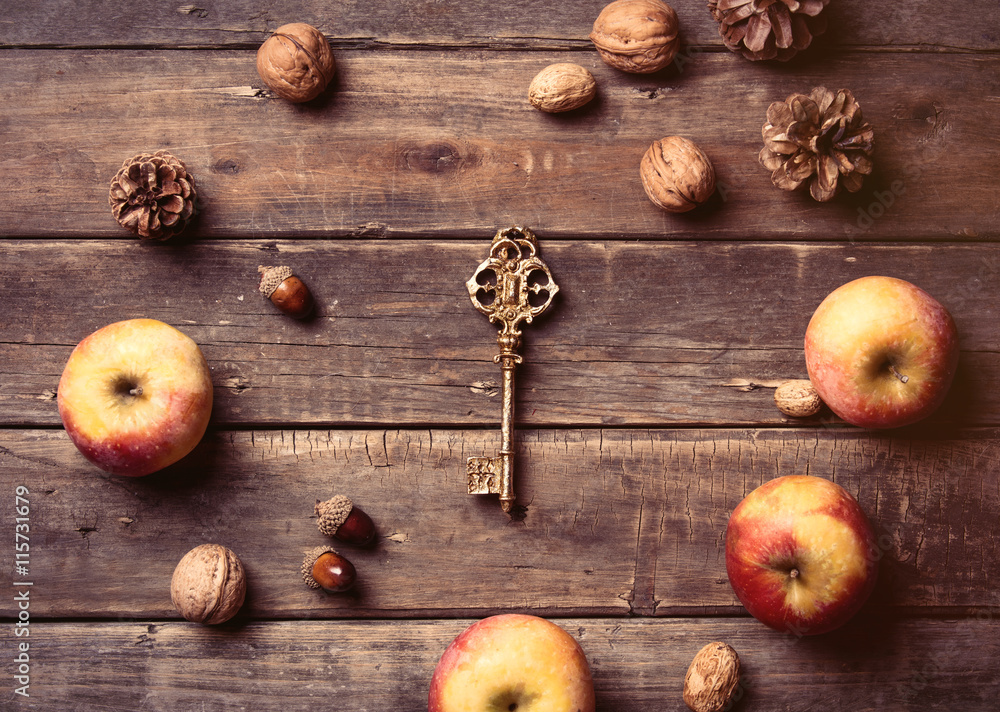 photo of the apples, golden key, fir-cones and nuts on the brown wooden background photo of the apples, golden key, fir-cones and nuts on the brown wooden background