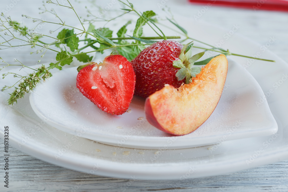 Strawberry and peach with mint on a white heard shape plate Strawberry and peach with mint on a white heard shape plate