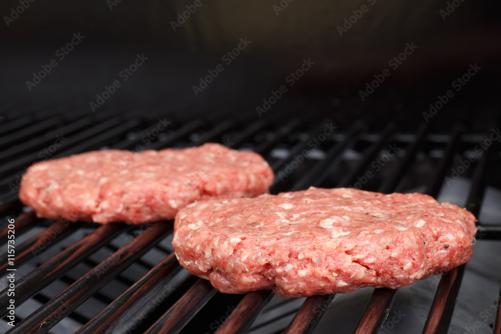 Raw hamburger patty on gas grill