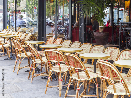 PARIS, FRANCE, on JULY 12, 2016. Little tables of typical Parisian cafe on the sidewalk near big window.